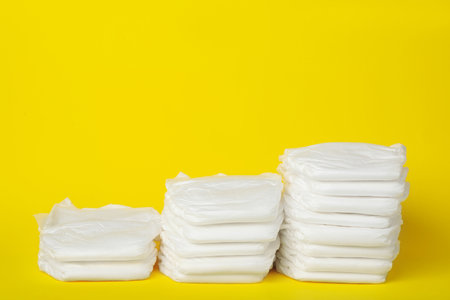Stacks of diapers on yellow background. Space for textの写真素材