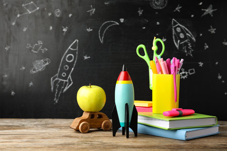 Bright toy rocket, car and school supplies on wooden tableの写真素材