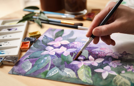 Woman painting flowers with watercolor at table, closeupの写真素材