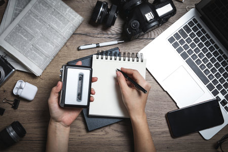 Journalist with voice recorder working at wooden table, top viewの写真素材
