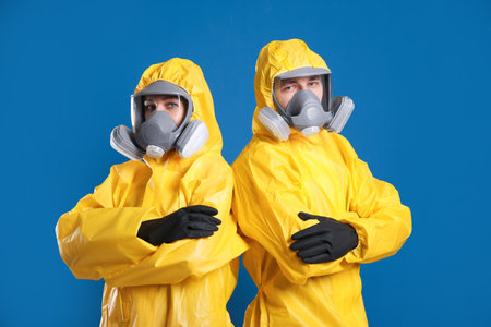 Man and woman wearing chemical protective suits on blue background. virus researchの写真素材