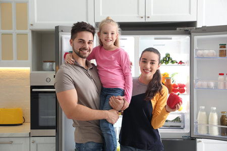 Happy family near open refrigerator in kitchenの写真素材