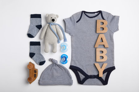 Flat lay composition with child's clothes and word Baby on white table