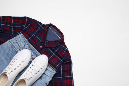 Stylish shirt, jeans and sneakers on white background, flat lay. Space for textの写真素材