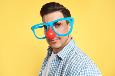 Man with funny glasses on yellow background. April fool's dayの写真素材