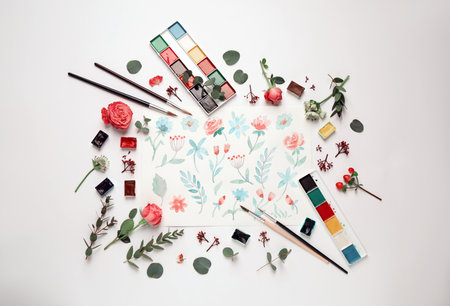 Flat lay composition with watercolor paints and floral picture on white backgroundの写真素材
