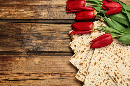 Tasty matzos and flowers on wooden table, flat lay with space for text. Passover (Pesach)の写真素材