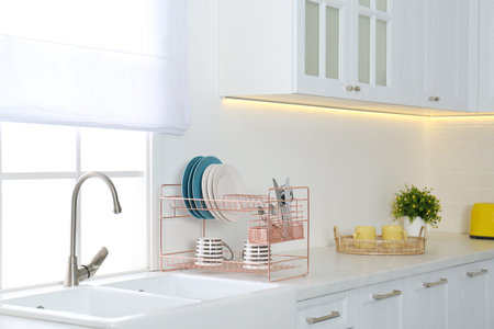 Clean dishes on drying rack in modern kitchen interiorの写真素材