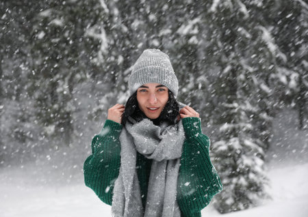 Young woman wearing warm clothes outdoors on snowy day. winter holidays