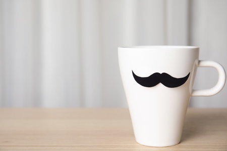 Cup with paper mustache on wooden table, space for text. happy father's dayの写真素材