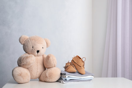 Child's clothes and toy bear on white table indoors, space for textの写真素材