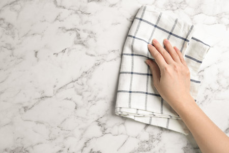Woman wiping white marble table with kitchen towel, top view. Space for textの写真素材