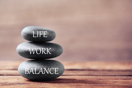 Work life balance concept. Stacked stones on wooden table, space for textの写真素材