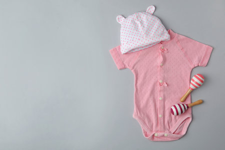 Child's cap, bodysuit and toys on gray background, flat lay with space for textの写真素材