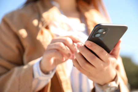 Woman holding Black smartphone outdoors, closeupの写真素材