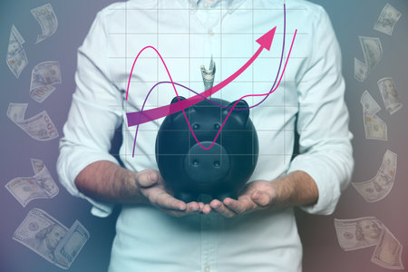 Young man with piggy bank and flying dollar banknotes on gray background, closeupの写真素材