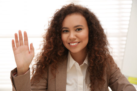 Happy African-American woman using video chat in office, view from web cameraの写真素材