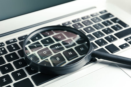 Magnifying glass on keyboard of modern laptop, closeup. Search conceptの写真素材