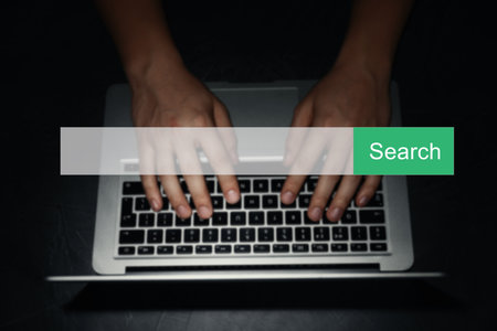 Search bar of internet browser and man working with laptop in darkness, top viewの写真素材