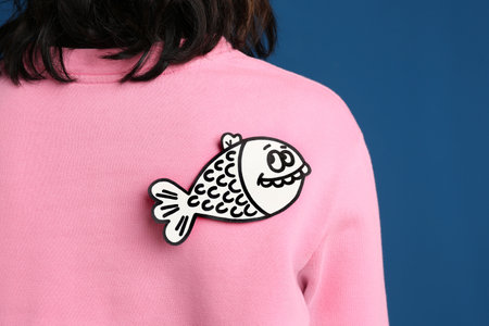 Woman with paper fish on back against blue background, closeup. April fool's dayの写真素材