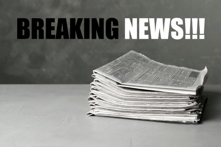 Phrase Breaking News and stack of newspapers on light gray stone table. Journalist's workの写真素材