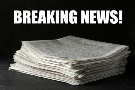 Phrase Breaking News and stack of newspapers on dark stone table. Journalist's workの写真素材