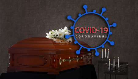 Coronavirus deaths. Funeral casket with white lilies at gray wall