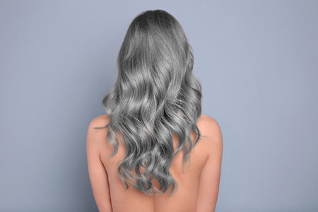 Woman with gray hair on grey background, back viewの写真素材