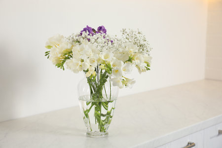 Beautiful bouquet with fresh freesia flowers in vase on cabinet indoorsの写真素材