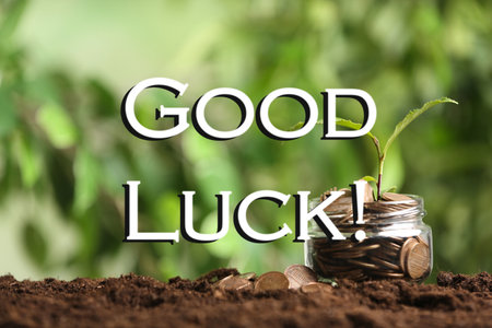 Coins with green plant and phrase GOOD LUCK on blurred green backgroundの写真素材