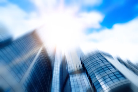 Blurred view of modern skyscraper with tinted windows against blue sky, low angle view. Building corporationの写真素材