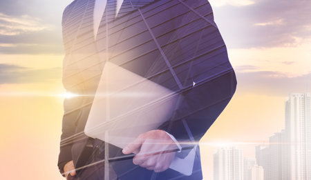 Double exposure of businessman with laptop and cityscape, closeupの写真素材