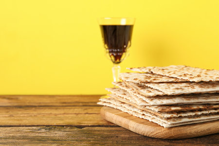 Passover matzos and glass of wine on wooden table, space for text. Pesach celebrationの写真素材