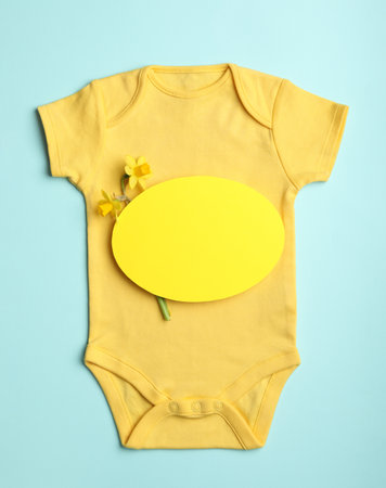Child's bodysuit, flowers and card with space for text on light blue background, top viewの写真素材