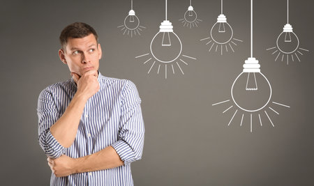 Lightbulbs illustration and thoughtful man in casual outfit on gray background. business ideasの写真素材