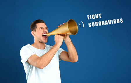 Handsome man with megaphone on blue background. Fighting with Coronavirus