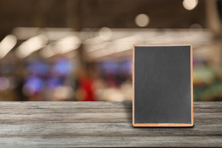Blank small blackboard on wooden table in cafe, mockup for menu designの写真素材