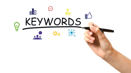 Woman writing word KEYWORDS on transparent board against white background, closeupの写真素材