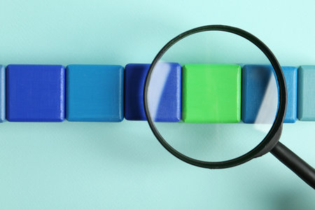 Magnifying glass and colorful cubes on light blue background, top view. Search conceptの写真素材