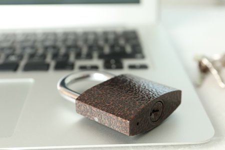 Metal lock and laptop on table, closeup. Protection from cyber attacks