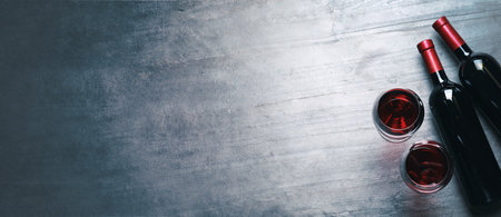 Glasses and bottles with red wine on color background, flat lay. banner designの写真素材