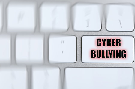 Top view of defocused laptop keyboard and phrase CYBER BULLYING on white button, closeupの写真素材