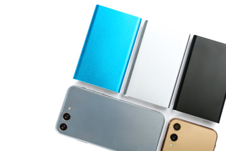 Mobile phones and portable chargers on white background, top view