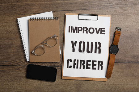 Flat lay composition with words IMPROVE YOUR CAREER, smartphone and stationery on wooden tableの写真素材