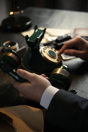 Detective dialing number on vintage telephone at table, closeupの写真素材