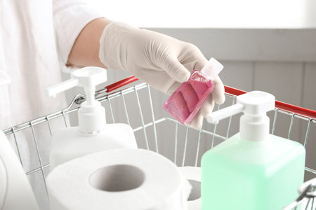 Woman with shopping basket full of antiseptics and toilet paper, closeup. Panic caused by virusの写真素材