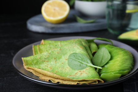 Delicious spinach crepes with avocado on black table, closeupの写真素材