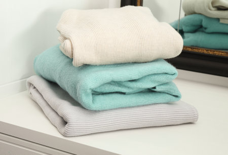 Stack of folded clothes on cabinet indoors