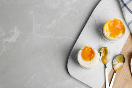 Soft and medium boiled chicken eggs on light gray marble table, flat lay. Space for text