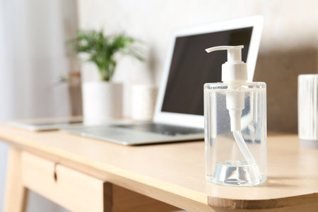 Dispenser bottle with antiseptic gel on table in office. Space for textの写真素材